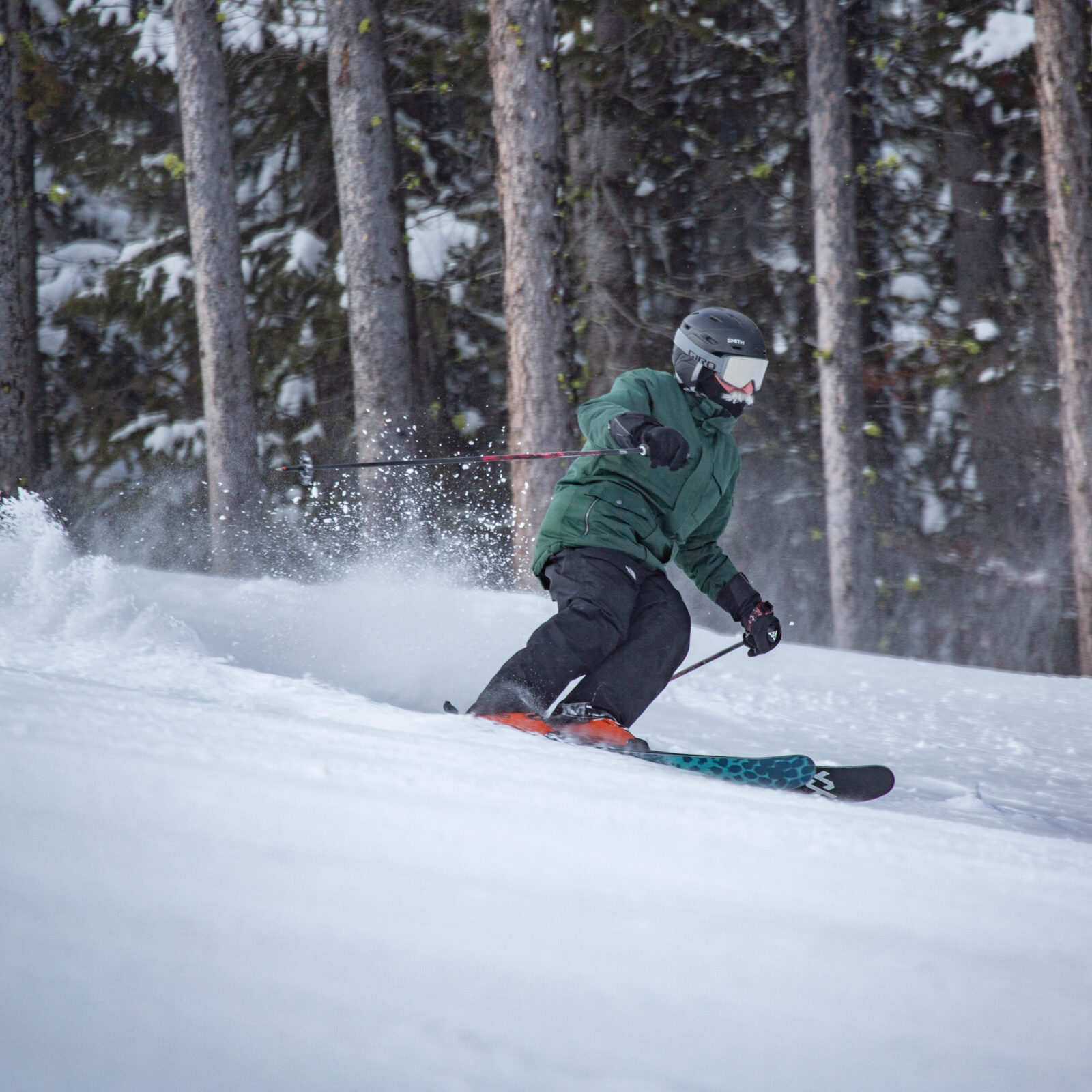 Skier in green and black carving under chair 3