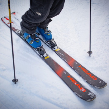 Close up of HEAD rental ski equipment package on snow including skis, boots, and poles.