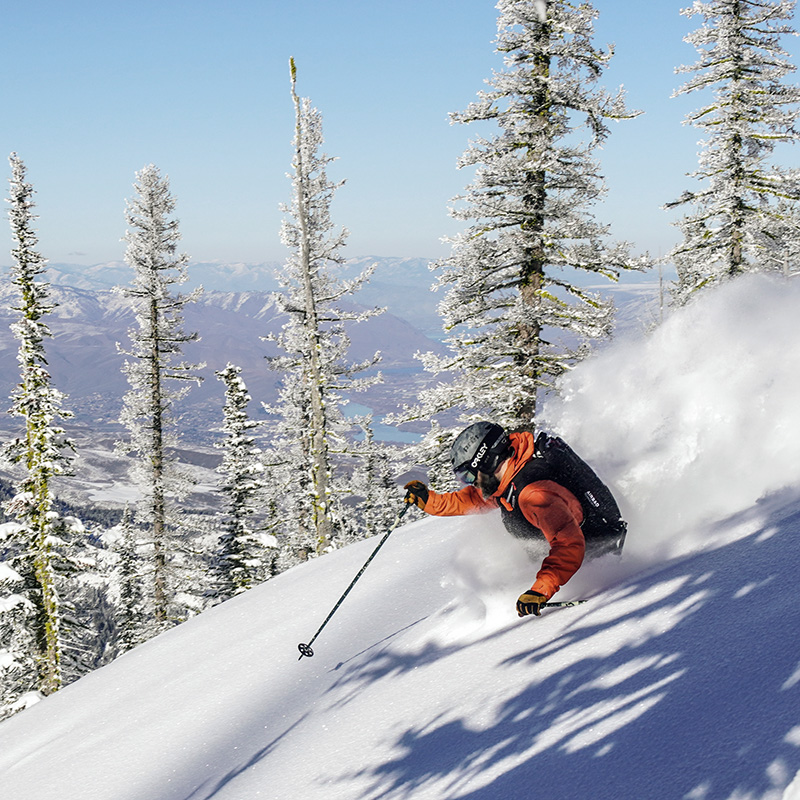 Skier making powder turn at Mission Ridge with river view below.