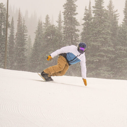 Snowboarder carving a deep turn on Tumwater ski trail at Mission Ridge.