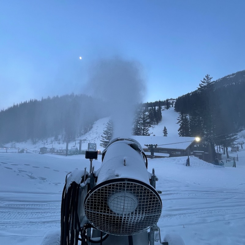 Snow gun at Mission Ridge Base Area with Chair 4 terrain and moonrise in the background.