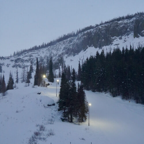 A distant shot of the Lower Chak Chak trail at Mission Ridge in the evening with the lights on.