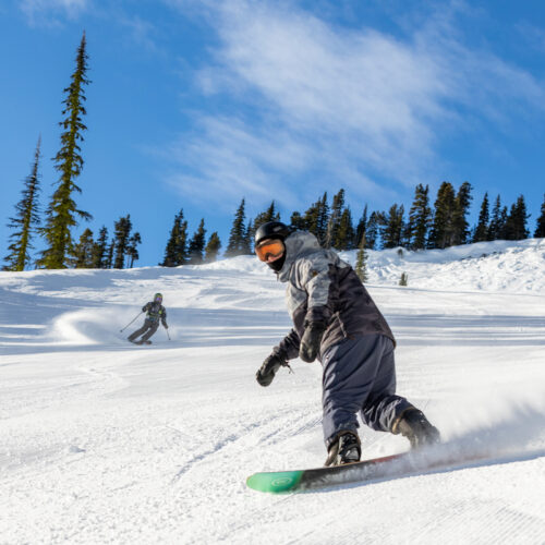 A snowboarder descends a sunny, snowy slope at Mission Ridge.