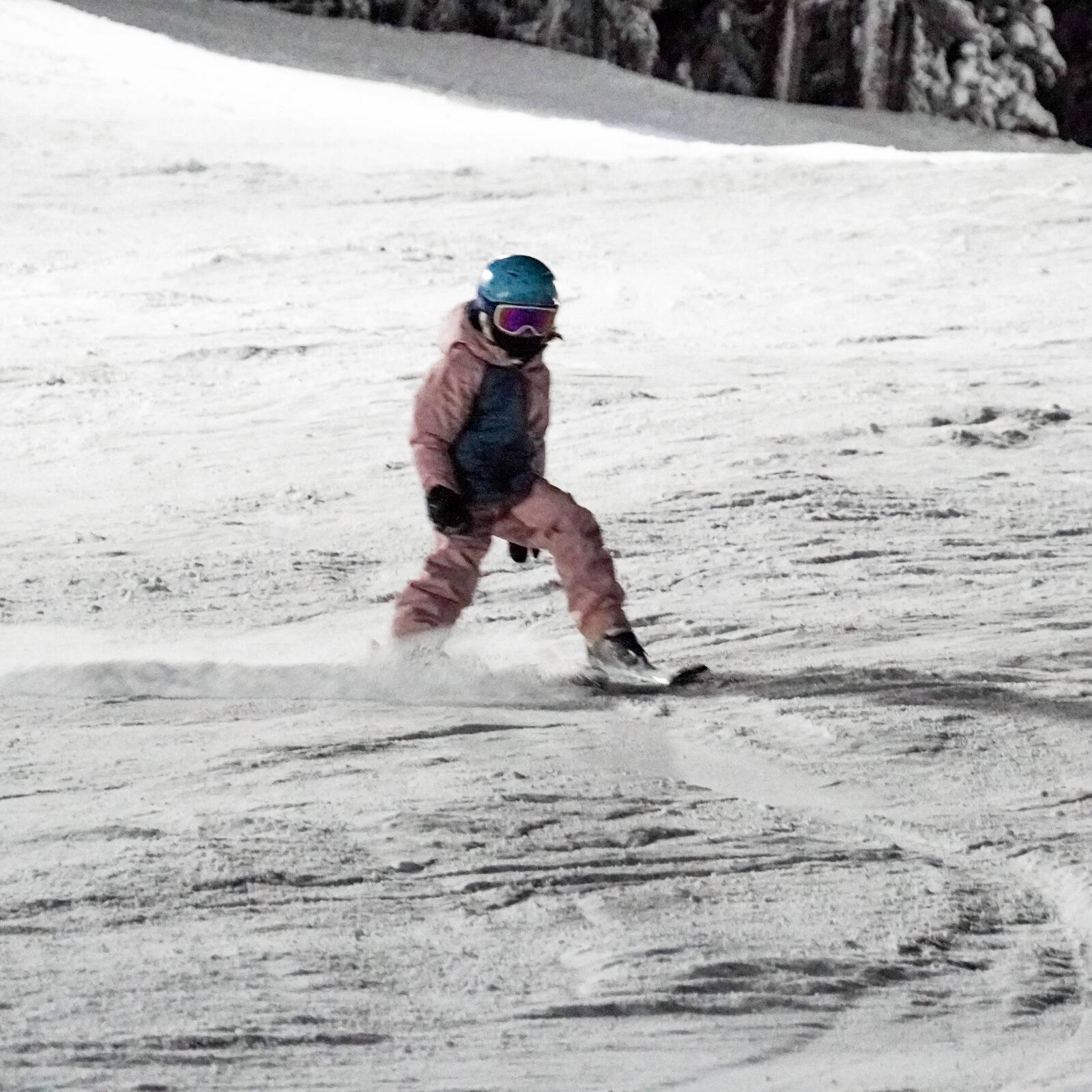 Child in pink jacket and blue helmet making ski turn on Tumwater run at Mission Ridge.