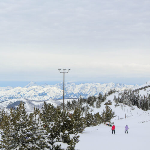 two skiers in pink ski past a foggy mountain view