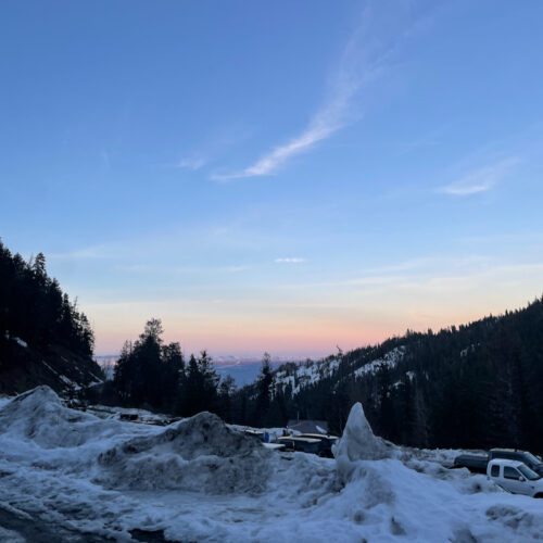 A sunset at Mission Ridge, with mostly clear skies in the background and a snowbank in the foreground.