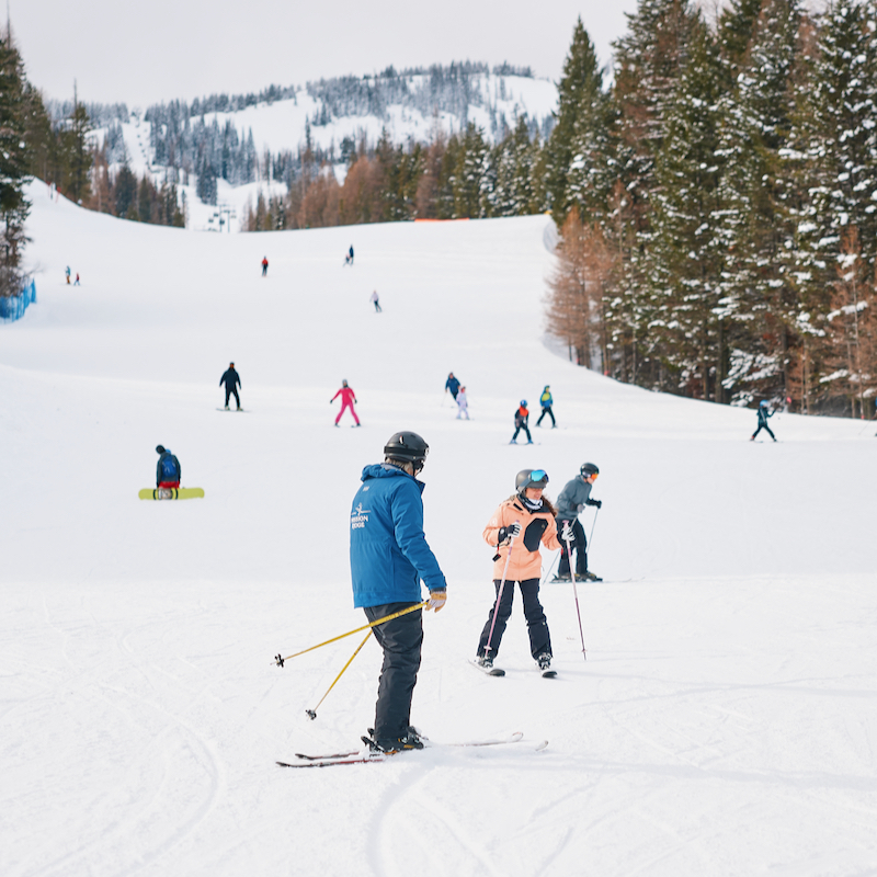 Skiers descend the Mimi trail at Mission Ridge, with an instructor and student in the foreground.